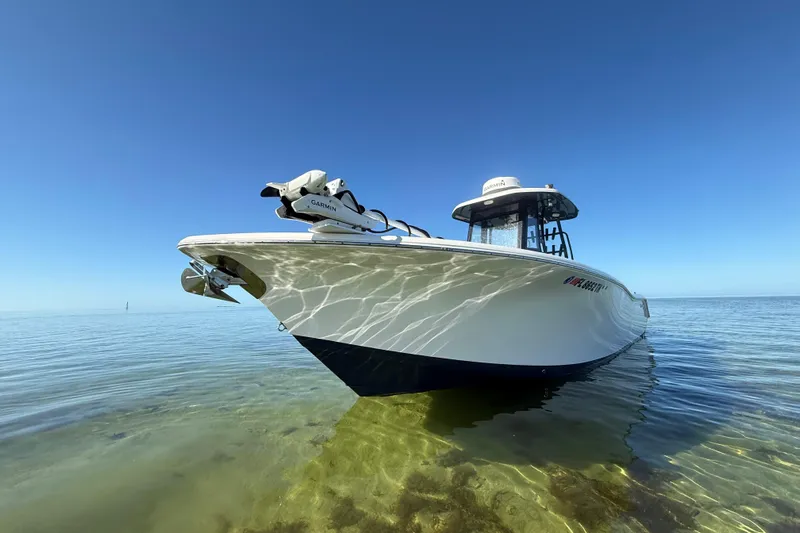  Yacht Photos Pics 2022 Tidewater 292 CC Adventure boat on clear, shallow water under blue sky.