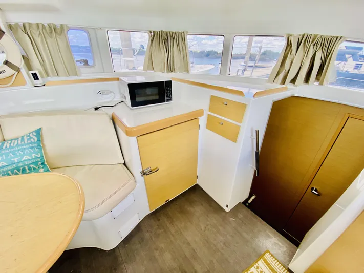 Finally Found Yacht Photos Pics Interior of 2014 Lagoon 380 S2 catamaran with seating, microwave, and storage cabinets.