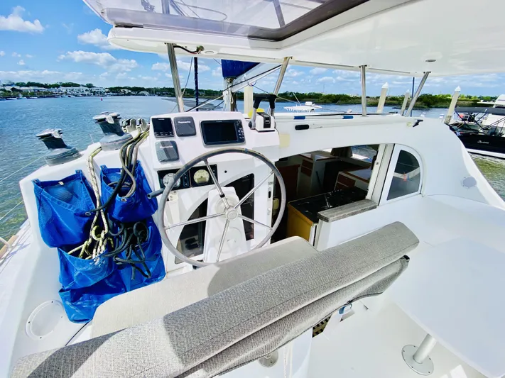 Finally Found Yacht Photos Pics Helm of 2014 Lagoon 380 S2 catamaran with navigation equipment, docked by a scenic waterfront.