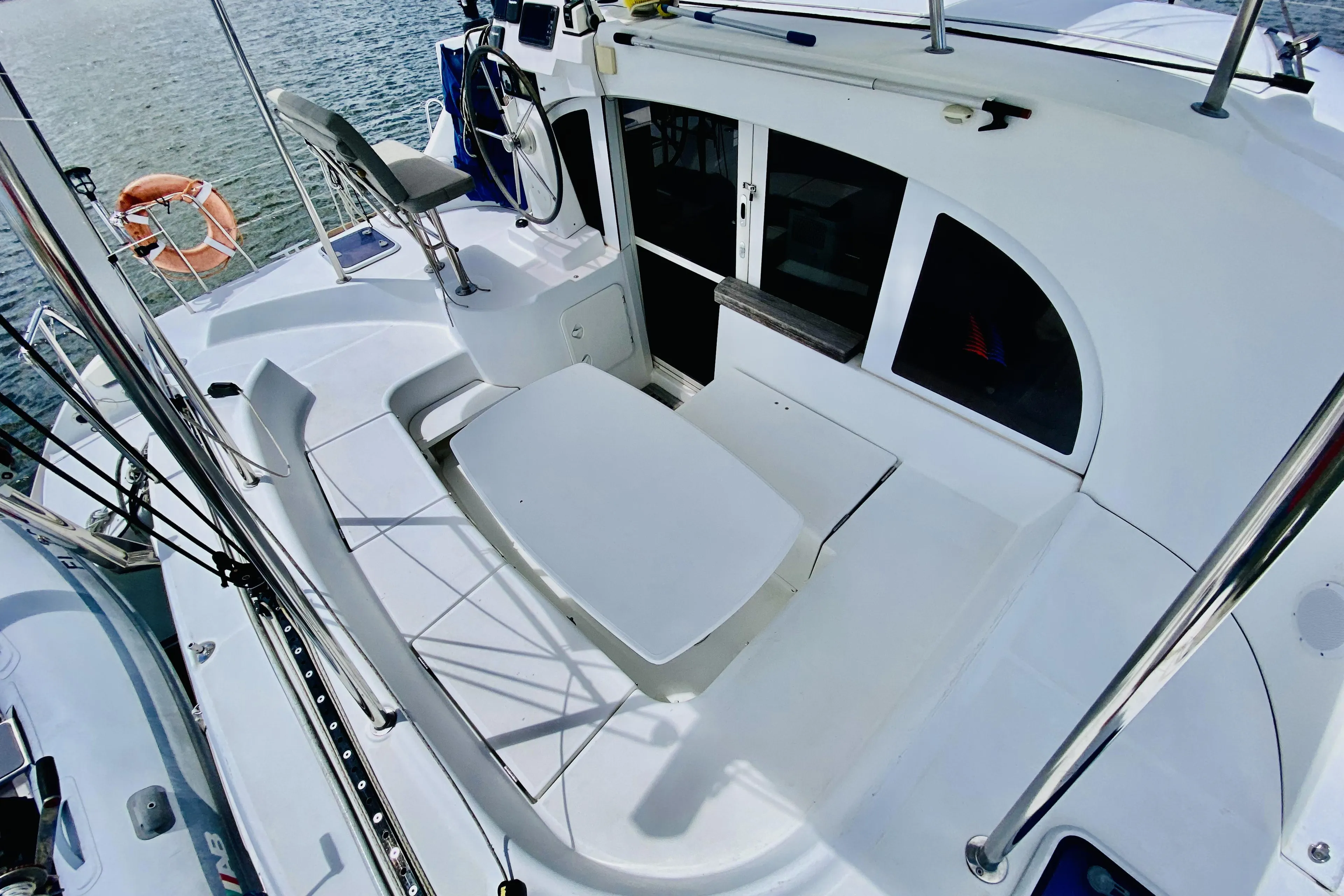 2014 Lagoon 380 S2 catamaran cockpit with seating and helm, docked by the water.