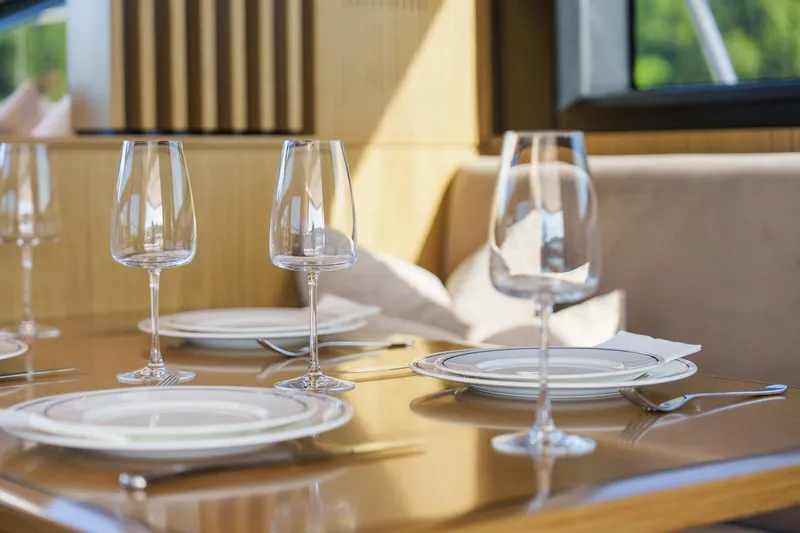 2023 Pearl 62 Luxury Yacht Yacht Photos Pics Elegant dining setup on Pearl 62 yacht, 2023 model, with wine glasses and plates.