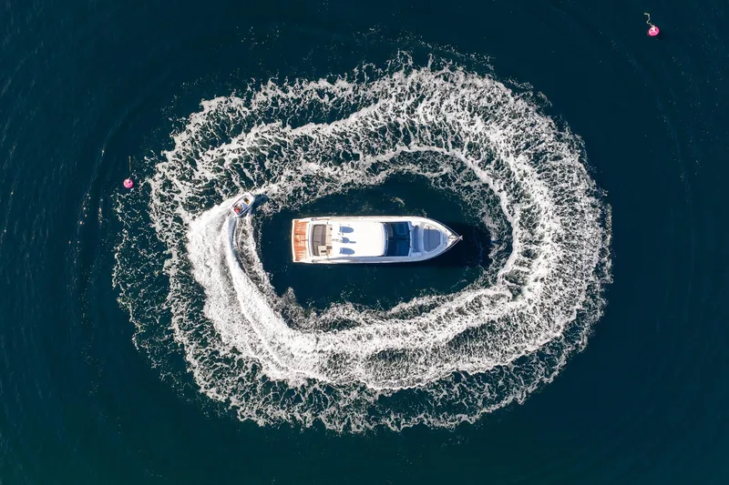 2023 Pearl 62 Luxury Yacht Yacht Photos Pics Aerial view of 2023 Pearl 62 yacht creating circular wake patterns in the water.