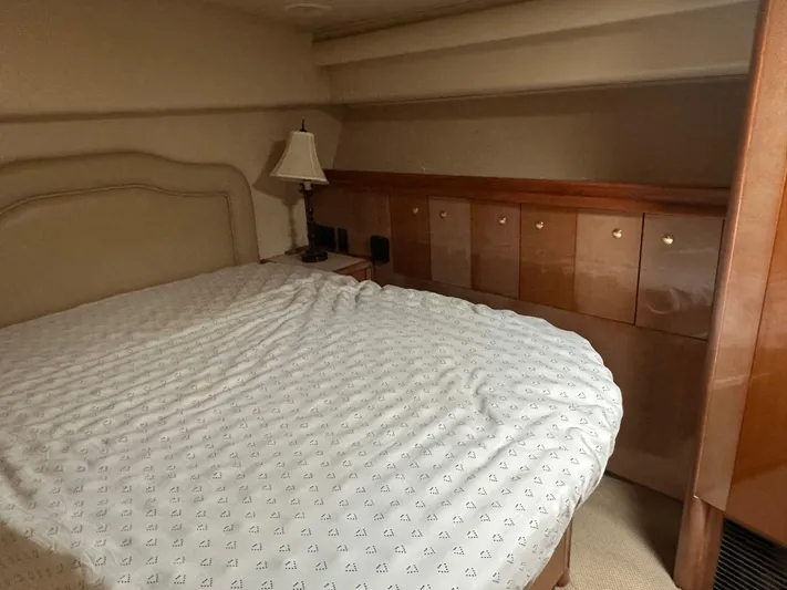  Yacht Photos Pics 2004 Viking 52 Convertible yacht bedroom with bed, lamp, and storage cabinets.