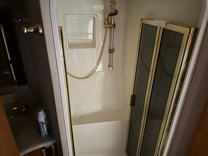  Yacht Photos Pics Shower area in a 2004 Viking 52 Convertible yacht with gold trim and glass doors.