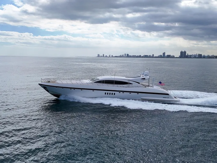  Yacht Photos Pics Luxury 2002 Mangusta 108 yacht cruising on open water with city skyline in background.