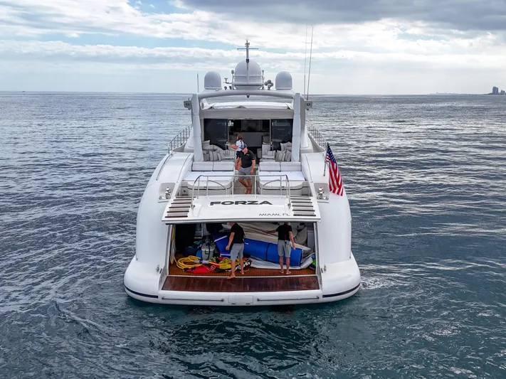  Yacht Photos Pics Luxury 2002 Mangusta 108 yacht on open sea, rear view with American flag.