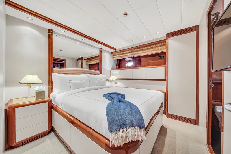 Yacht Photos Pics Luxurious bedroom interior on 2002 Mangusta 108 yacht, featuring elegant wood accents and cozy bedding.