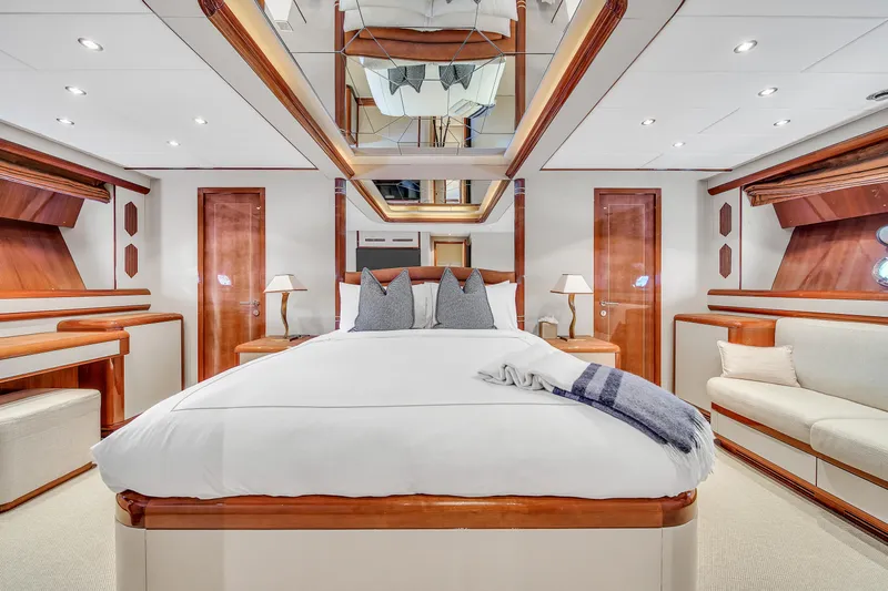  Yacht Photos Pics Luxurious bedroom interior on 2002 Mangusta 108 yacht, featuring elegant wood accents and plush bedding.