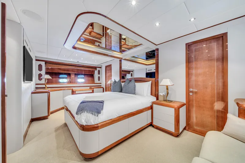  Yacht Photos Pics Luxurious bedroom interior of 2002 Mangusta 108 yacht with elegant wood accents.