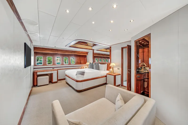  Yacht Photos Pics Luxurious bedroom interior of 2002 Mangusta 108 yacht with elegant wood accents.
