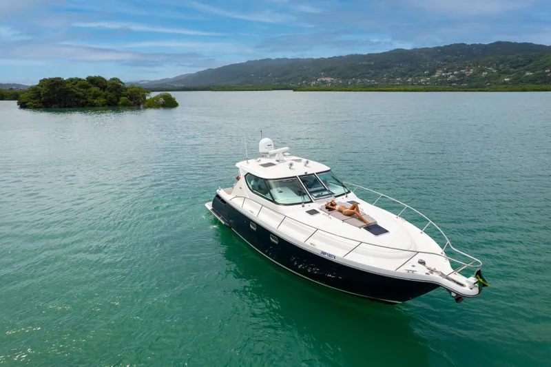 T 2 Yacht Photos Pics 2006 Tiara Yachts 4300 Sovran cruising on serene waters with lush green hills in the background.