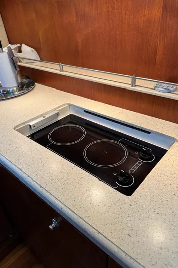 T 2 Yacht Photos Pics 2006 Tiara Yachts 4300 Sovran kitchen with sleek electric stovetop and wooden cabinetry.