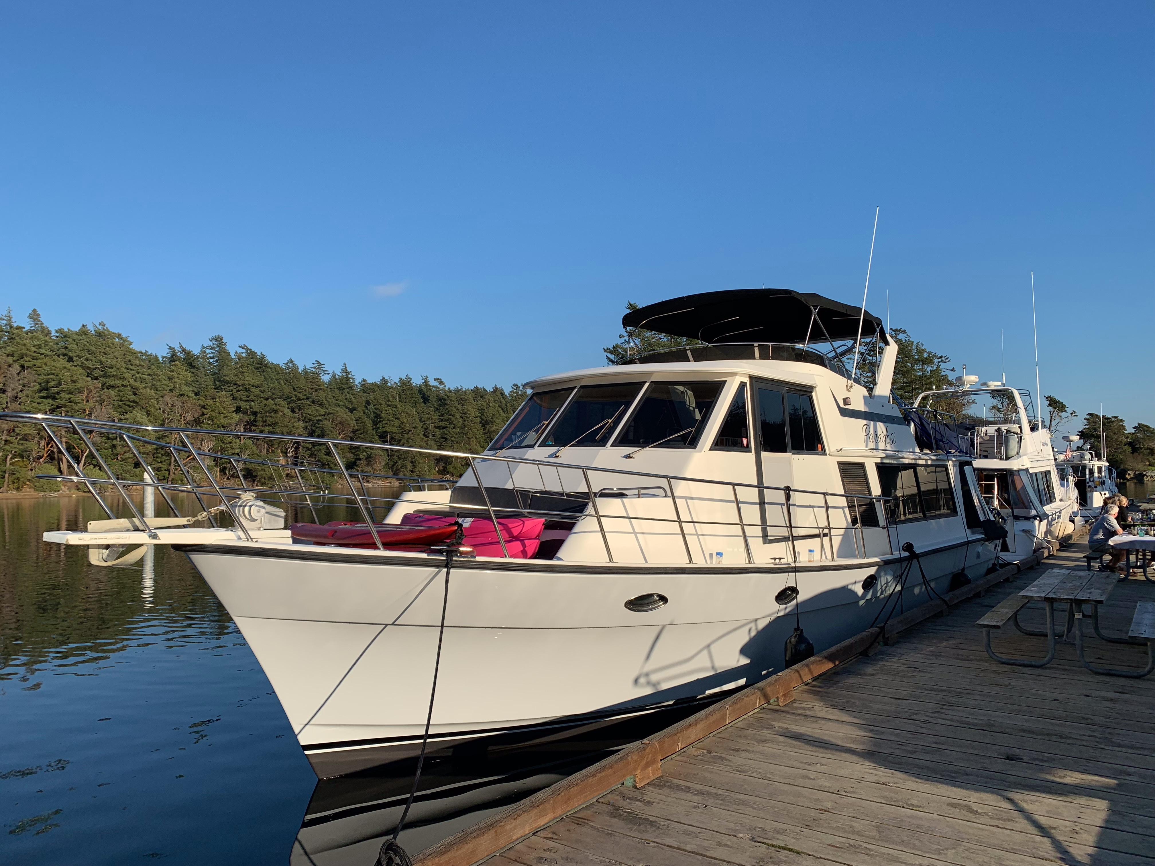 Nova 4500 yacht from 1990 docked by a serene lakeside with clear blue skies.