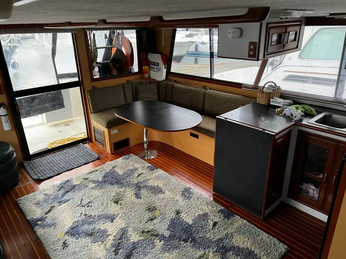 Paradosi Yacht Photos Pics Cozy interior of a 1990 Nova 4500 boat with seating, table, and kitchenette.