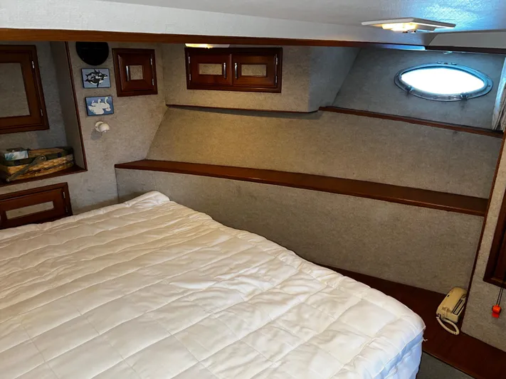 Paradosi Yacht Photos Pics Cozy bedroom interior in a 1990 Nova 4500 boat with wood accents and porthole window.