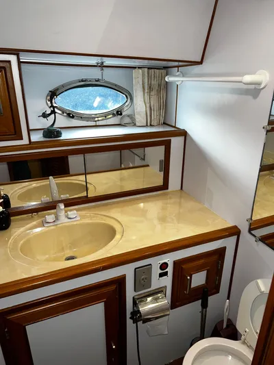 Paradosi Yacht Photos Pics Compact 1990 Nova 4500 bathroom with sink, mirror, and porthole window.