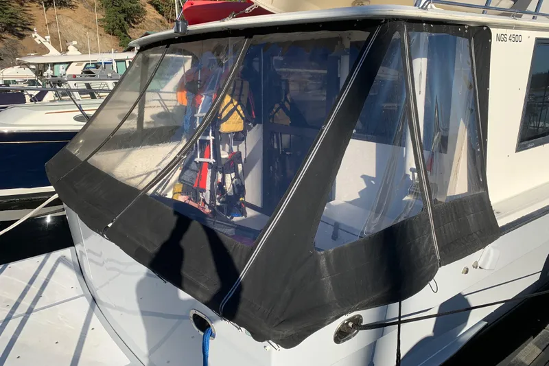 Paradosi Yacht Photos Pics Nova 4500 boat from 1990 with black canvas enclosure in a marina setting.