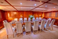 Luxurious yacht dining room with elegant table setting, white chairs, and wooden paneling, 1982 Husumer Shipyard.