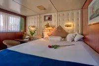 Luxurious ship cabin with plush bedding, vintage decor, and soft lighting, built by Husumer Shipyard in 1982.