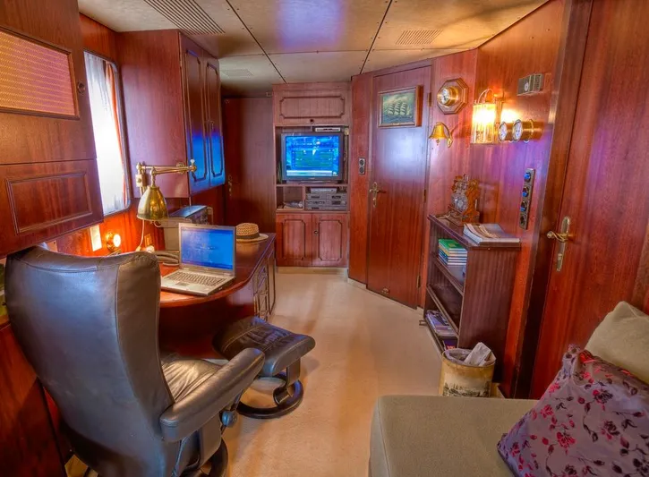 Sanssouci Star Yacht Photos Pics Luxurious 1982 Husumer Shipyard cabin with wooden interior, desk, and cozy seating area.