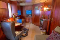 Luxurious 1982 Husumer Shipyard cabin with wooden interior, desk, and cozy seating area.