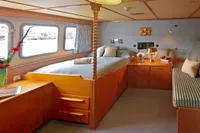 Luxurious 1982 Custom Husumer Shipyard cabin with cozy bed, wooden furnishings, and large windows.