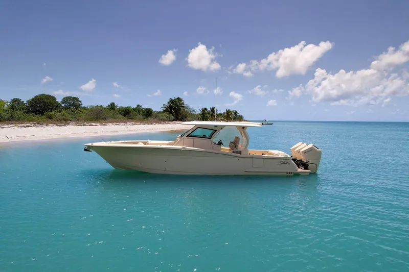  Yacht Photos Pics 2024 Scout 377 LXF boat anchored near a tropical beach with clear blue water.