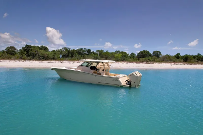  Yacht Photos Pics 2024 Scout 377 LXF boat anchored in clear turquoise water near a sandy beach.
