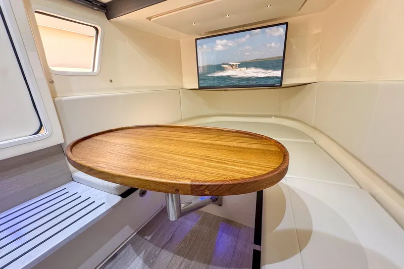  Yacht Photos Pics 2024 Scout 377 LXF cabin interior with wooden table and wall-mounted screen.