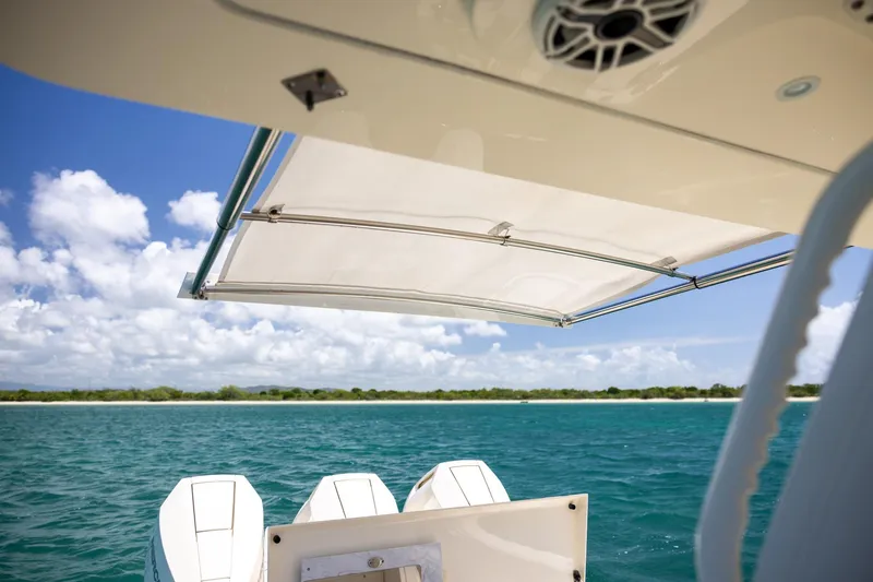  Yacht Photos Pics 2024 Scout 377 LXF boat with canopy, cruising on clear blue water under a sunny sky.