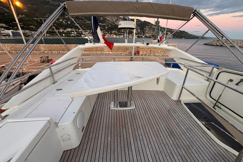  Yacht Photos Pics 2018 Prestige 560 yacht deck with table, overlooking scenic coastal view at sunset.