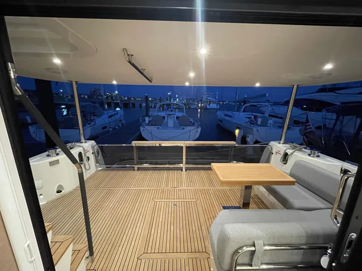  Yacht Photos Pics 2024 Beneteau Grand Trawler 62 aft deck with seating and table at night.