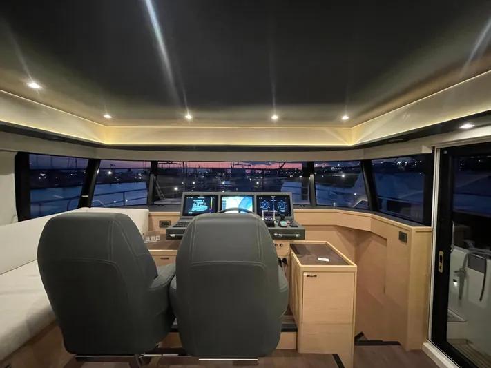  Yacht Photos Pics 2024 Beneteau Grand Trawler 62 helm with modern controls and panoramic windows at sunset.