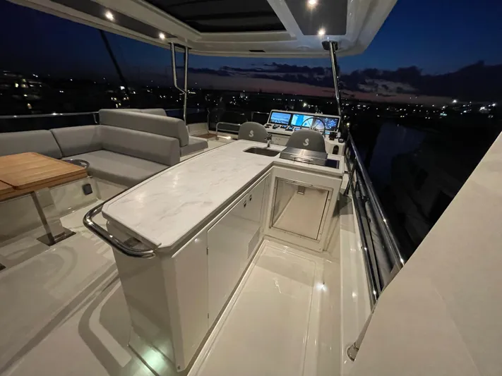  Yacht Photos Pics Luxurious 2024 Beneteau Grand Trawler 62 yacht interior at dusk, featuring elegant seating and helm.