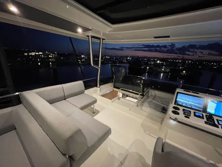  Yacht Photos Pics Luxurious interior of 2024 Beneteau Grand Trawler 62 at night, featuring modern seating and controls.