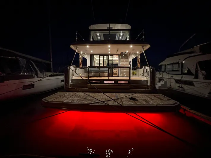  Yacht Photos Pics 2024 Beneteau Grand Trawler 62 with illuminated deck at night, docked in marina.