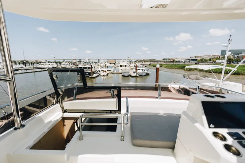 Yacht Photos Pics Flybridge view from 2024 Beneteau Grand Trawler 62, overlooking marina with boats and clear sky.