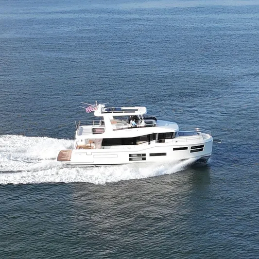  Yacht Photos Pics 2024 Beneteau Grand Trawler 62 cruising on open water, showcasing sleek design and luxury.