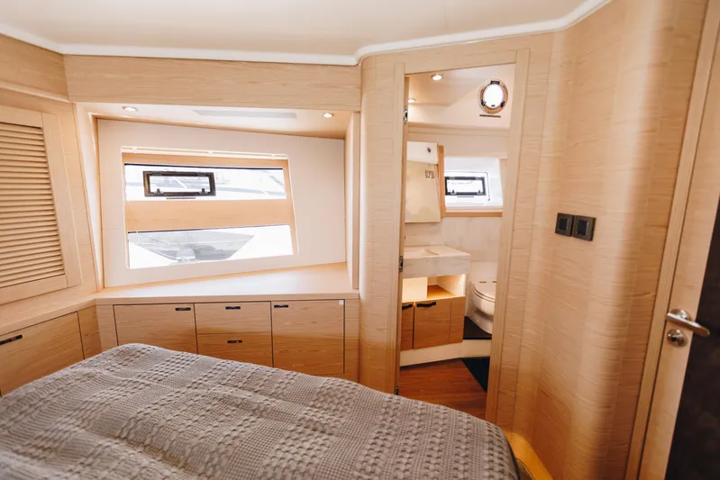  Yacht Photos Pics Luxurious interior of 2024 Beneteau Grand Trawler 62, featuring a cozy bedroom and modern bathroom.