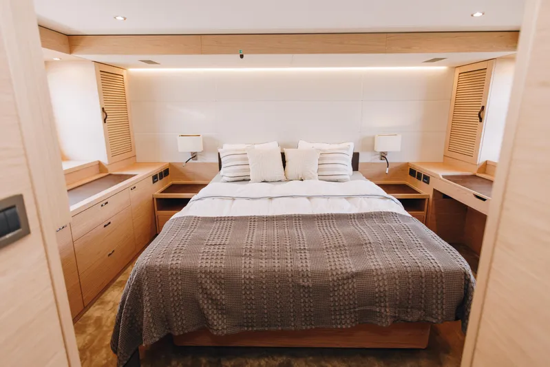  Yacht Photos Pics Luxurious bedroom interior of 2024 Beneteau Grand Trawler 62 yacht, featuring elegant wood finishes.