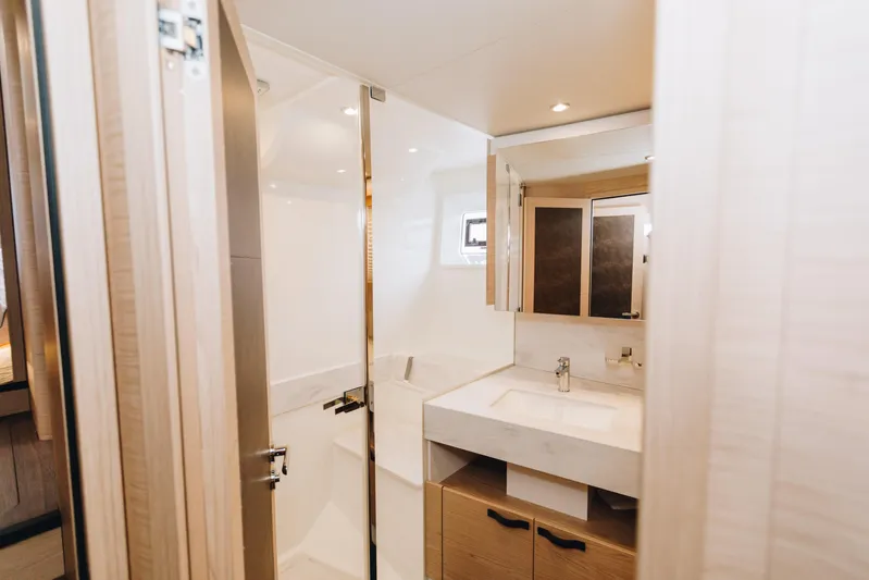  Yacht Photos Pics Luxurious bathroom in 2024 Beneteau Grand Trawler 62 yacht, featuring modern fixtures and elegant design.