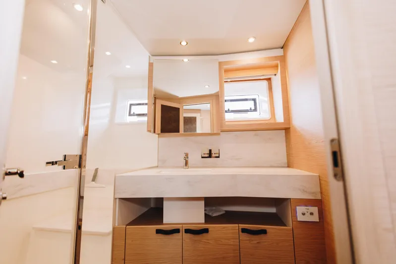  Yacht Photos Pics Luxurious bathroom interior of 2024 Beneteau Grand Trawler 62 yacht, featuring modern fixtures and wood accents.