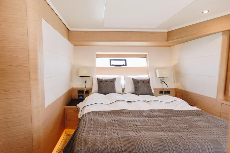  Yacht Photos Pics Luxurious bedroom interior of 2024 Beneteau Grand Trawler 62 yacht, featuring elegant wood finishes.