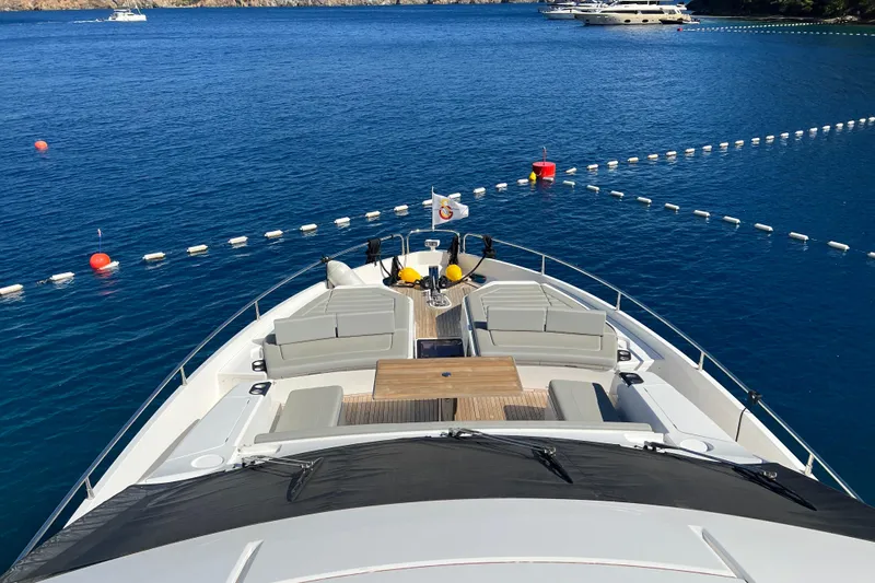 Enough Yacht Photos Pics Luxurious 2023 Sunseeker 76 Yacht on serene blue waters, featuring spacious deck seating.
