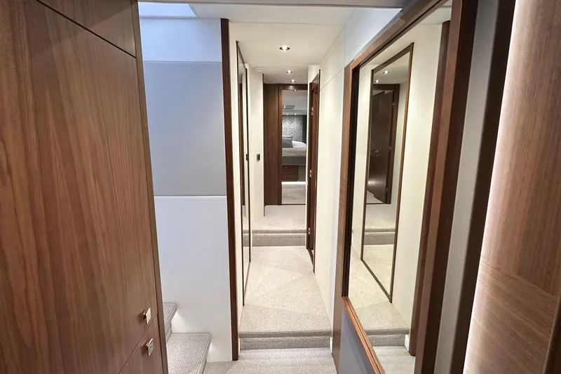 Enough Yacht Photos Pics Luxurious interior hallway of 2023 Sunseeker 76 Yacht with wood paneling and mirrors.