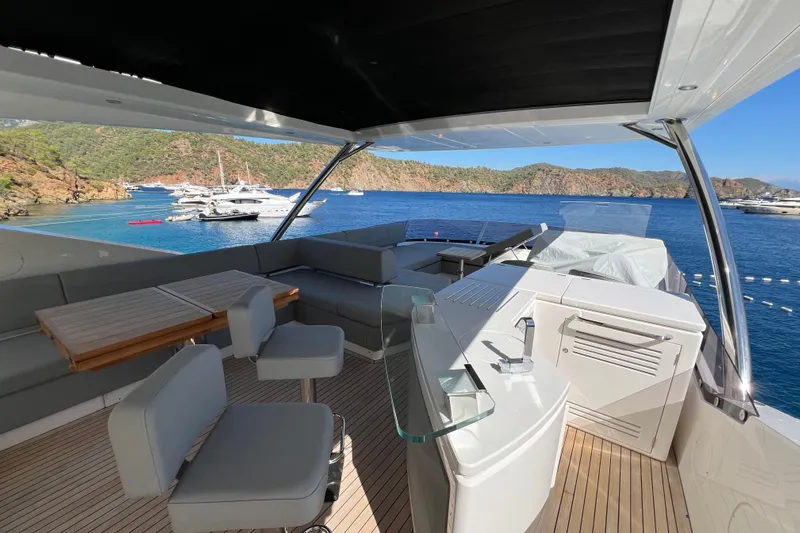 Enough Yacht Photos Pics Luxurious 2023 Sunseeker 76 Yacht deck with seating, overlooking scenic coastal waters.