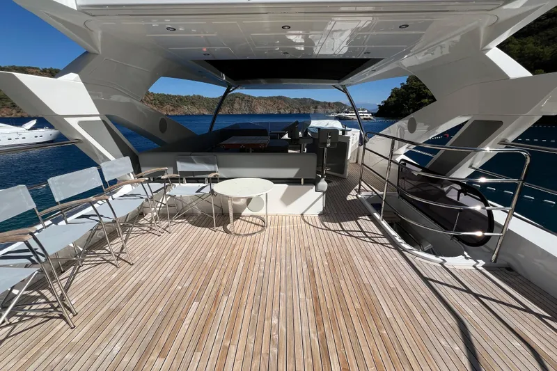 Enough Yacht Photos Pics Luxurious 2023 Sunseeker 76 Yacht deck with seating, overlooking serene waters and distant yachts.