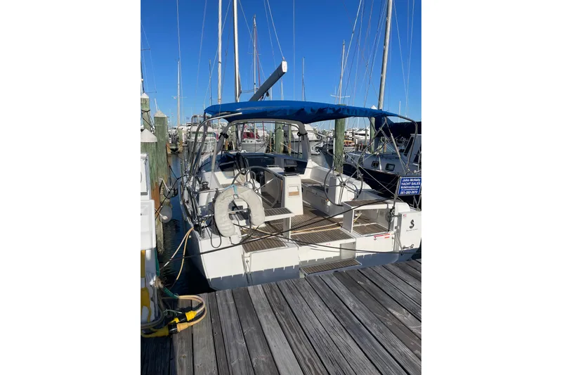 Hummingbird Yacht Photos Pics 2017 Beneteau Oceanis 38.1 sailboat docked at marina, featuring blue canopy.