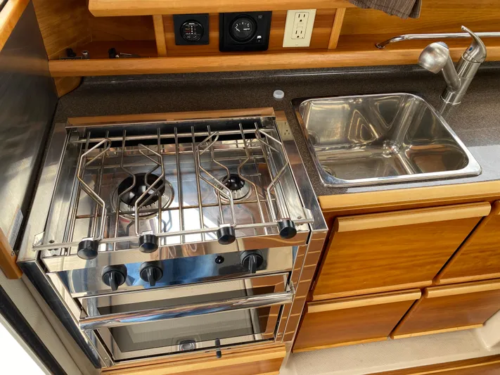  Yacht Photos Pics 2017 Cutwater C-28 boat kitchen with stove, sink, and wooden cabinetry.