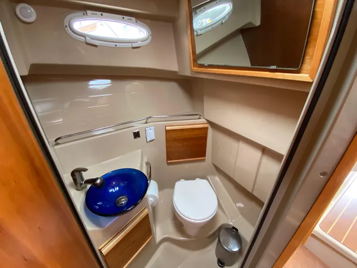  Yacht Photos Pics 2017 Cutwater C-28 boat bathroom with blue sink, toilet, and wooden accents.